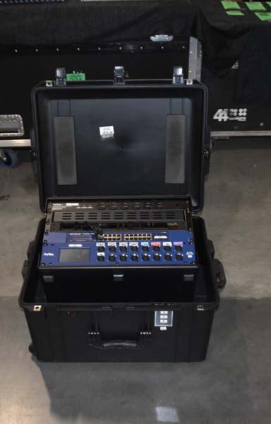 Open black case with a blue electronic device inside, on a concrete floor.