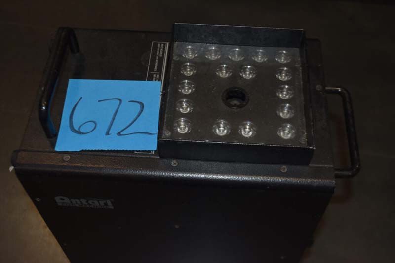 Black Antari device with a blue sticky note labeled "672" and circular lights on top.