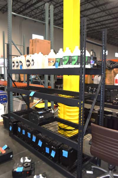 Warehouse shelf with cleaning supplies and equipment cases.